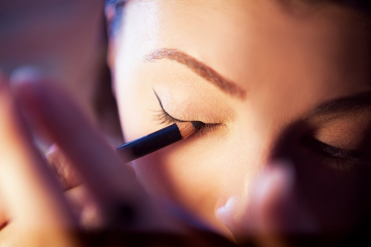 Woman applying eyeliner corrective eyeliner tattoo