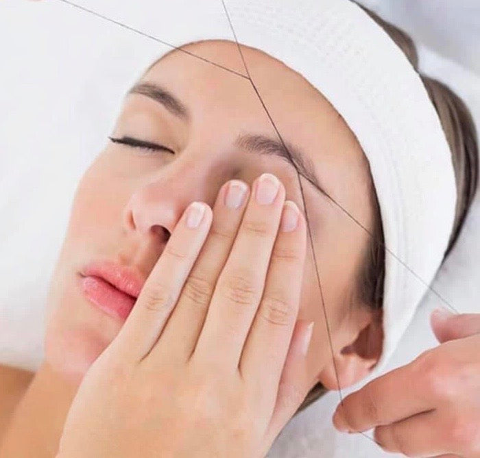 Woman with a white towel on her head, touching her face with one hand.