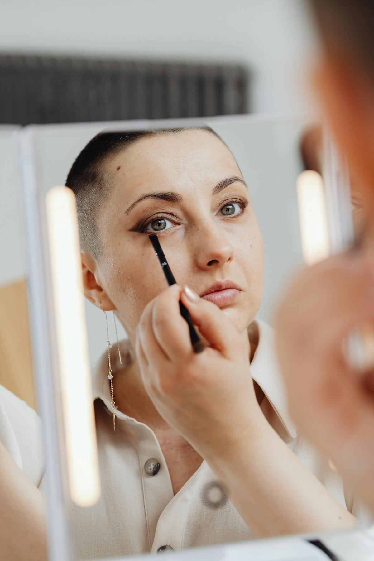 Woman putting on eye makeup eyeliner tattoo touch-up